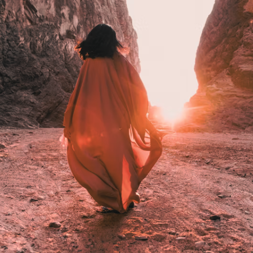 image of woman walking into sun set in flowy dress